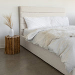 Load image into Gallery viewer, Justin Storage Bed-Tall, Cream by Style In Form. Lifestyle shot of bed in white room with concrete floor, bed is dressed with duvet, pillows and fur throw, there is a wood stump end table on the left side with a white vase on it. View from left end side of the bed. Shop vintage &amp; new home décor, lighting &amp; home furnishings as well as novelty gifts &amp; pet accessories online at blueigloo.ca

