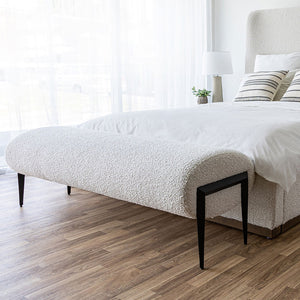 Fisher Bench shown at the end of a bed upholstered in the same fabric as the bench with a white duvet and striped off-white throw cushions. Shop benches and stools online at blueigloo.ca.