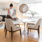 Load image into Gallery viewer, Flute Oval Marble Top Dining Table-Full Size by Style In Form. Lifestyle shot showing table in a room with a women placing a tray with wine glasses and decanter on it.  4 chairs are placed around the table. Shop vintage &amp; new home décor, lighting &amp; home furnishings as well as novelty gifts &amp; pet accessories online at blueigloo.ca
