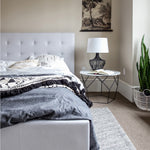 Load image into Gallery viewer, June Storage Bed, Horizon Grey by Style In Form. Lifestyle shot showing dressed bed in room with side table on right side with lamp and open book on table. View from end of bed. Shop vintage &amp; new home décor, lighting &amp; home furnishings as well as novelty gifts and pet accessories online at blueigloo.ca 
