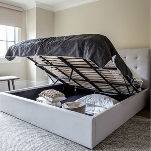 June Storage Bed, Horizon Grey by Style In Form. Lifestyle shot showing dressed bed in room with mattress lifted, showing items in storage area of bed. View from right bottom corner of bed. Shop vintage & new home décor, lighting & home furnishings as well as novelty gifts and pet accessories online at blueigloo.ca