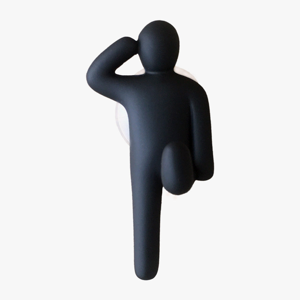 Resin Figure Hook, Black. Front view. A suction hook shaped like a person, right arm raised touching side of head, left arm straight by side. Left leg lifted at waist height, right leg straight down. Shop suction hooks and other bath accessories at blueigloo.ca