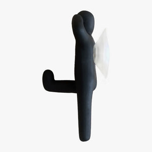 Resin Figure Hook, Black. Side view. A suction hook shaped like a person, right arm raised touching side of head, left arm straight by side. Left leg lifted at waist height, right leg straight down. Shop suction hooks and other bath accessories at blueigloo.ca