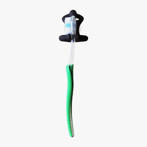 Resin Figure Toothbrush Holder by Milk Design. Shown in black holding a green & clear toothbrush on a white background. Front view. Shop suction hooks and bathroom accessories at blueigloo.ca